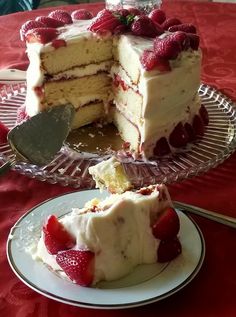 a piece of cake with white frosting and strawberries on top is being cut