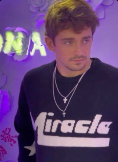 a young man wearing a black shirt and silver necklace