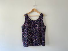 ⚡️Beautiful vintage sleeveless blouse, top with floral print, navy blue color with violet, dark pink and green flowers and leafs. ⚡️In excellent vintage condition. ⚡️ Fits best- S-M-L. ⚡️Reference model size M, height - 178 cm, weight - 60 kg. ⚡️Measurements: - Armpit to armpit, flat taken: 21,6 inch // 55 cm. - Length from armpit to bottom: 15 inch // 38 cm. - Length: 25,6 inch // 65 cm. ⚡️All items come from a smoke free home. ⚡️Please write me your phone number, Your number will be used only Casual Purple Tank Top With Floral Print, Purple Floral Print Summer Tank Top, Summer Purple Floral Print Tank Top, Purple Cotton Sleeveless Blouse, Sleeveless Purple Cotton Blouse, Patterned Sleeveless Top With Floral Print, Patterned Floral Print Sleeveless Tops, Vintage Sleeveless Blouse For Spring, Sleeveless Top With Vintage Print For Summer