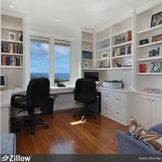 an office with two chairs and a desk in front of a window overlooking the ocean