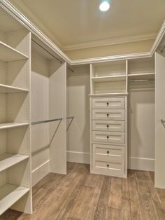 an empty walk in closet with lots of shelves and drawers on the wall, along with wooden flooring