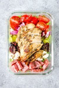 a salad with meat, tomatoes and lettuce is shown in a plastic container