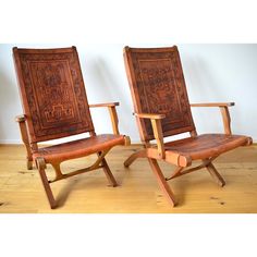 two wooden chairs sitting next to each other on top of a hard wood floored floor