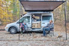 a man sitting in a chair next to a van with an awning over it