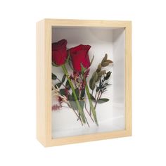 two red roses in a wooden box on a white background with greenery and dried flowers