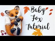 a baby fox figurine sitting on top of a white board with autumn leaves