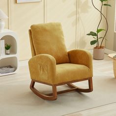 a brown rocking chair sitting on top of a wooden floor next to a potted plant