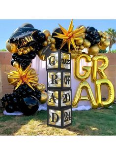 some black and gold balloons in the shape of letters that read grad on them