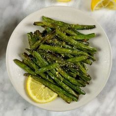 asparagus on a white plate with lemon wedges