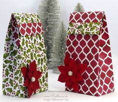 two christmas bags with poinsettis on them sitting in front of a tree