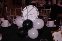 black and white balloons are on top of a table with silverware, wine glasses, and plates