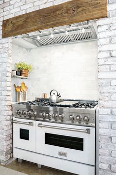 a white stove top oven sitting inside of a kitchen next to a brick wall with an open door