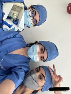 two women in scrubs and masks standing next to each other with one pointing at the camera