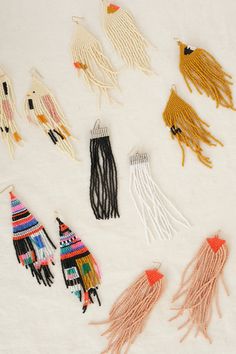 several different types of beaded earrings on a white surface with fringes and tassels