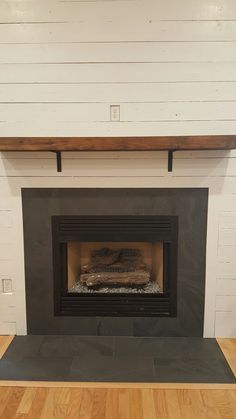 a fire place in a room with white walls and wood flooring on the side