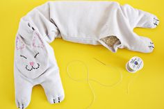 a stuffed animal laying on top of a yellow surface next to some sewing needles and thread