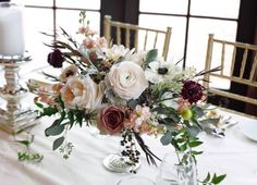 a vase filled with flowers sitting on top of a table next to a white candle