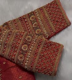 two pieces of red and gold cloth on a white surface