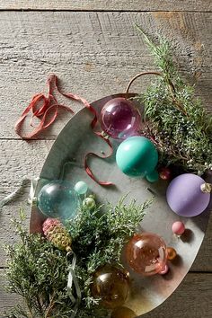 an assortment of vases and plants are arranged on a round metal platter that sits on a wooden table