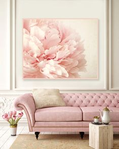 a living room with a pink couch and large flower painting on the wall above it