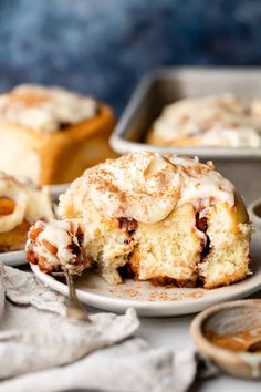 a cinnamon roll with icing on a plate next to other pastries and spoons