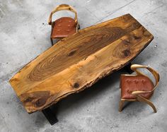 a wooden table with two chairs and a bench made out of tree trunks on concrete