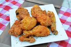 fried chicken on a white plate sitting on a red and white checkered tablecloth