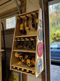 a garage with tools hanging from the ceiling and shelves filled with construction equipment in front of a car