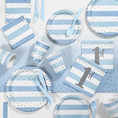 a blue and white table setting with plates, napkins, spoons and forks