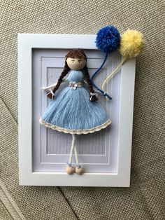 a doll in a blue dress holding two pom poms