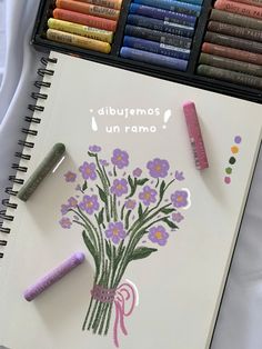 an open notebook with crayons and flowers on it