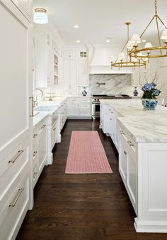 a large kitchen with white cabinets and marble counter tops, along with a pink rug on the floor