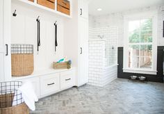 a white bathroom with black and white tile on the walls, cabinets, and drawers