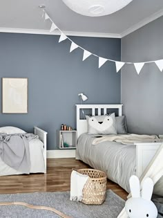 a bedroom with blue walls and white bedding has bunting flags hanging from the ceiling