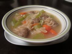 a bowl of soup with meatballs, carrots, celery and noodles