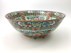 a large bowl with floral designs on the inside and outside, sitting on a white surface