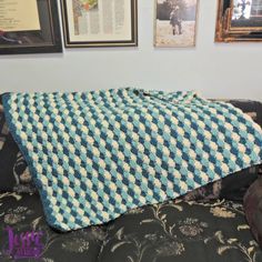 a blue and white blanket sitting on top of a couch next to framed pictures in a living room