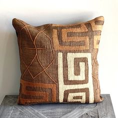 a brown and white pillow sitting on top of a wooden table next to a wall