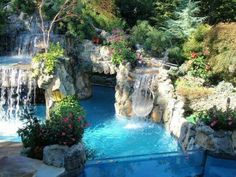 an outdoor pool with waterfall and water features