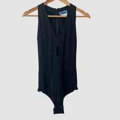 a black bodysuit hanging on a wooden hanger