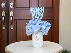 a mason jar filled with blue flowers sitting on top of a table next to a door