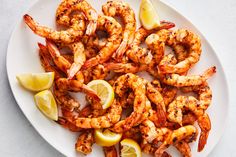 grilled shrimp with lemon wedges on a white plate