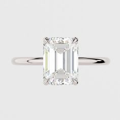 an emerald cut diamond engagement ring on a white background