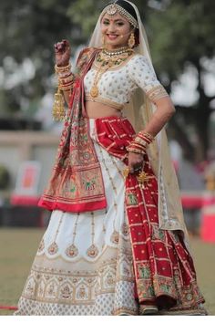 a woman in a red and white bridal outfit with her hand on her hip