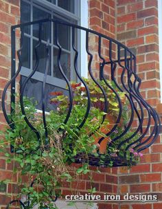 an iron balcony railing with potted plants on the ledge and windowsill above it