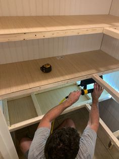 a man is working on shelves with tools