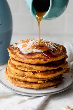 a stack of pancakes with syrup being poured on top