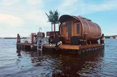 a floating house in the middle of water with trees on it's roof and other equipment