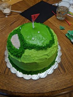 a cake with green frosting and a golf ball on top is sitting on a table