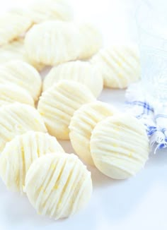 some white chocolates are on a table next to a blue and white cloth with a small piece of fabric in the background